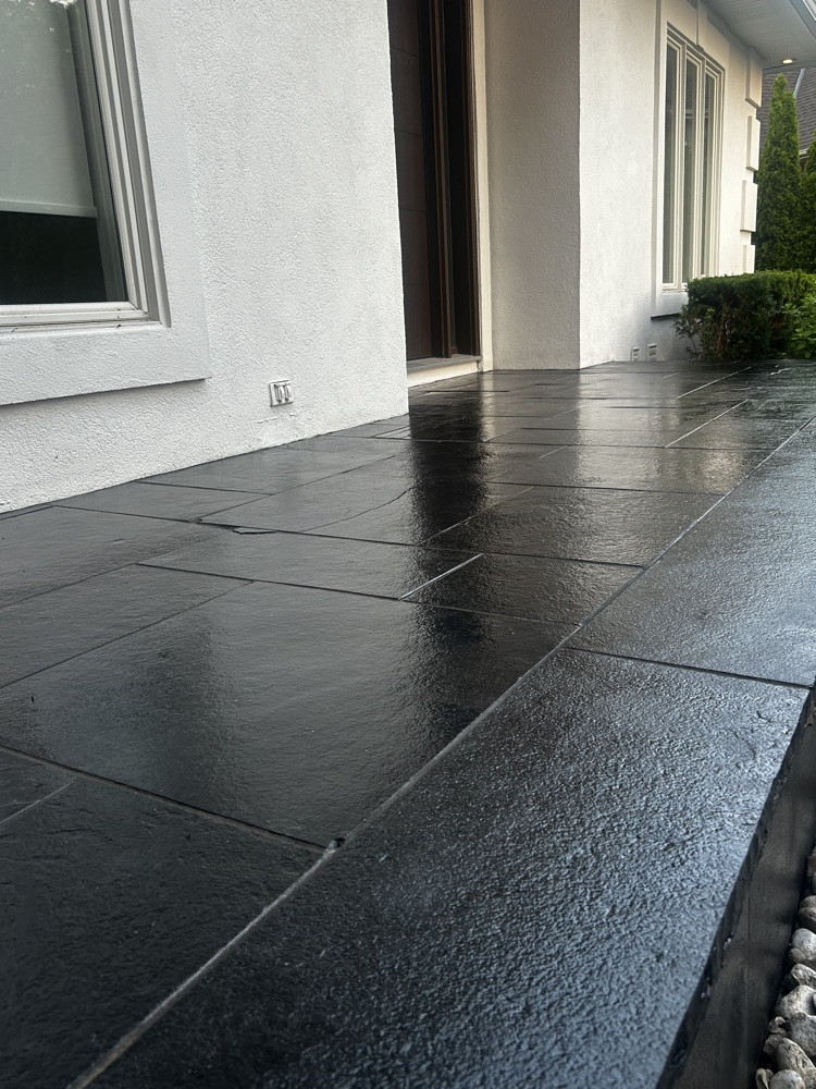 Sealed black natural-stone entry beside a white exterior